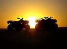 ATVs on dune at sunset
