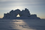 Iceberg with hole, backlit by setting sun