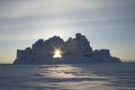 Iceberg with hole, backlit by setting sun