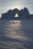 Iceberg with hole, backlit by setting sun