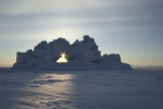 Iceberg with hole, backlit by setting sun