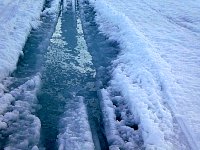 Water filled snowmobile trail on lake